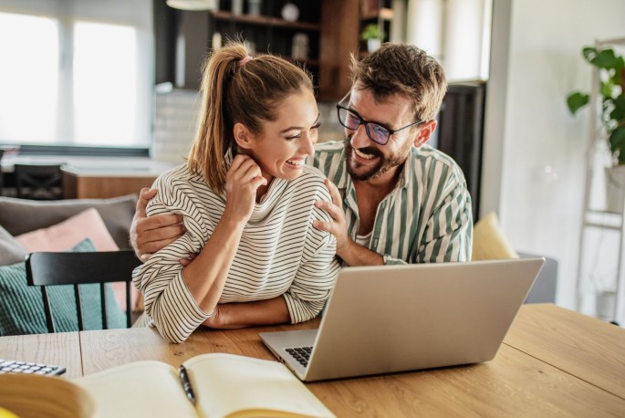 Stage-Image - Paar-lacht-vor-Laptop-Online-Sparen